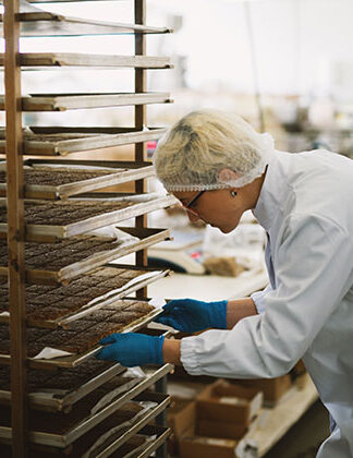 Photo of baker stacking sheets of baking on cooling racks.