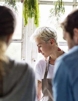 Photo of florist in an apron interacting with her clients. This is a stock photo to promote web design for small business owners.