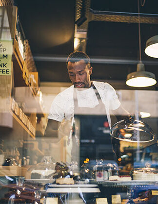 Photo of a cafe owner putting out the pastries for customers to buy. Stock photo promoting Sabourin Web & Media, one of the top Winnipeg web design companies.