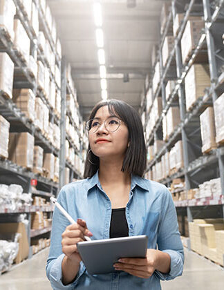 Photo of warehouse inventory manager making notes on a clipboard.